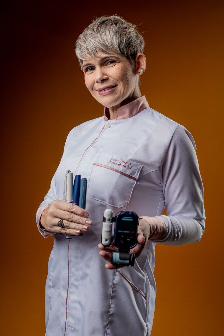 Taís Iunes, nutricionista especialista em Diabetes, segurando canetas de insulina e um glicosímetro